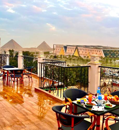 a balcony with tables and chairs with pyramids in the background at New Museum Guest House, Pyramids View in Cairo