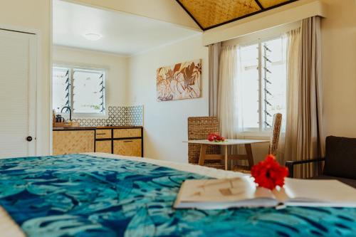 a bedroom with a blue bed and a table and window at Tai Roto Bay in Arutanga