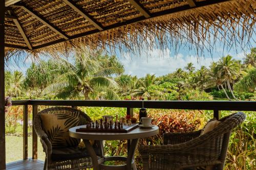 a table and chairs on a porch with a view at Tai Roto Bay in Arutanga