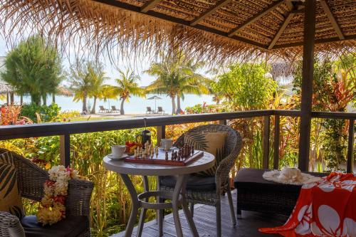 a table and chairs on a balcony with a view of the ocean at Tai Roto Bay in Arutanga