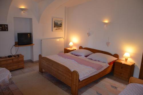 a bedroom with a bed and a tv and two lamps at Růžová chalupa u Šimánků in Rtyně v Podkrkonoší