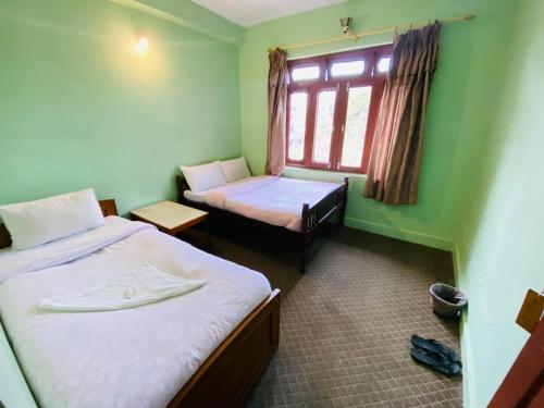 Habitación pequeña con 2 camas y ventana en HOTEL ICE VIEW POKHARA, en Pokhara