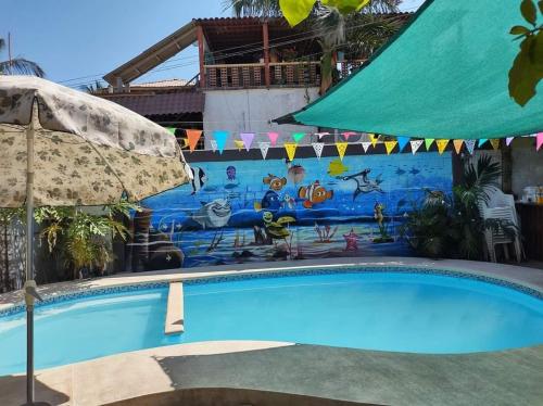 a swimming pool with an umbrella and a mural at Casa Jeymar in Coyuca