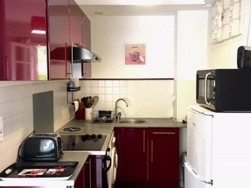 une cuisine avec des armoires rouges et un réfrigérateur blanc dans l'établissement Studio ensoleillé avec balcon, parking et WIFI - proche du centre d'Amélie-les-Bains-Palalda - FR-1-703-6, à Amélie-les-Bains-Palalda