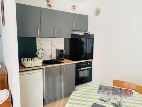 - une petite cuisine avec des placards gris et une table dans l'établissement Studio cosy avec balcon, parking et Wifi - 2 pers, proche thermes et centre ville - FR-1-703-11, à Amélie-les-Bains-Palalda