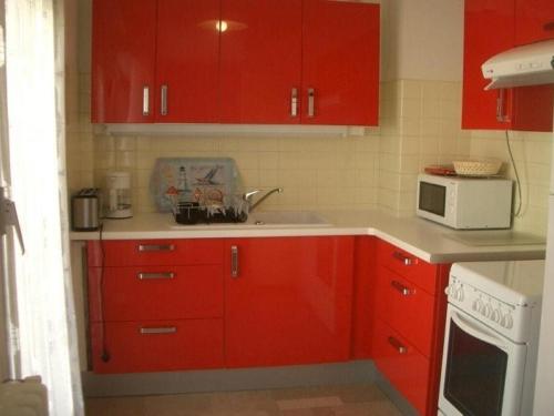 - une cuisine avec des placards rouges et un four micro-ondes blanc dans l'établissement Appartement F2 climatisé, balcon, proche Thermes d'Amélie-les-Bains - FR-1-703-21, à Amélie-les-Bains-Palalda