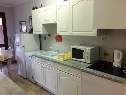 une cuisine avec des armoires blanches et un micro-ondes dans l'établissement F2 avec parking, terrasse & wifi à Amélie-les-Bains, animaux acceptés - FR-1-703-53, à Amélie-les-Bains-Palalda