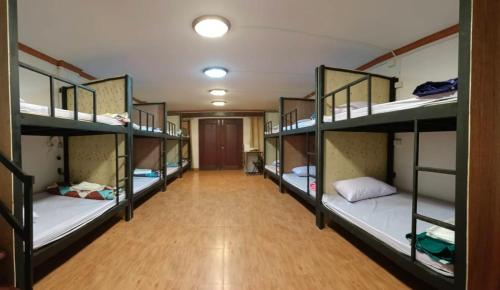 Pakse Backpacker Hostel2023 في باكسي: ممر مع العديد من الأسرّة ذات الطابقين في غرفة النوم