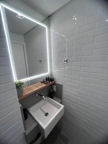 Baño blanco con lavabo y espejo en Studio Conceito centro Floripa, en Florianópolis