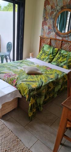 a bed with a colorful comforter and a mirror at Villa Mary Guest House in Saint-André