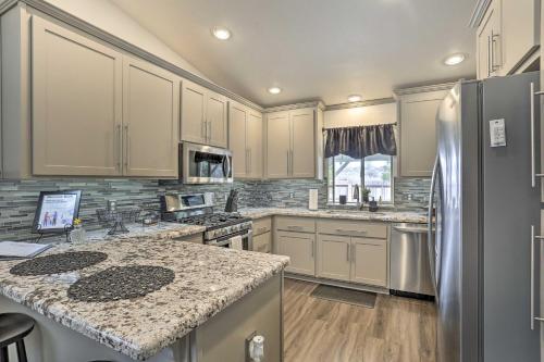 a kitchen with white cabinets and a stainless steel refrigerator at Redding Home with Patio Near Fishing! in Redding