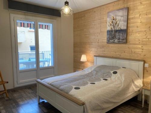 une chambre avec un lit et une grande fenêtre dans l'établissement F3 lumineux avec terrasse, garage, clim et ascenseur à 500m du centre et 800m des thermes - FR-1-703-85, à Amélie-les-Bains-Palalda