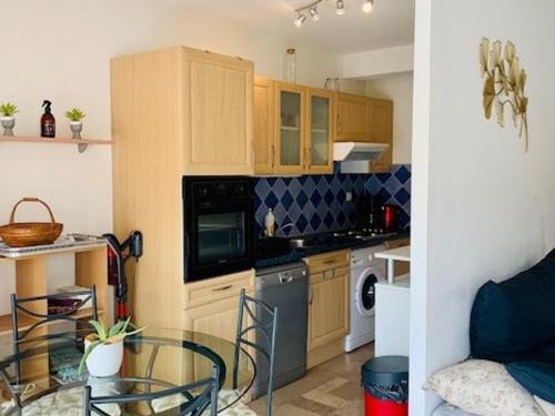 une cuisine avec des placards en bois et une table en verre dans l'établissement Appartement F2 cosy avec terrasse, plein sud, à 600m des cures et 400m du centre, animaux acceptés. - FR-1-703-79, à Amélie-les-Bains-Palalda