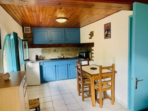 une cuisine avec des armoires bleues et une table et des chaises dans l'établissement Appartement Confortable en Pleine Nature à Arles-sur-Tech - Parking et Animaux Acceptés - FR-1-703-99, à Arles-sur-Tech