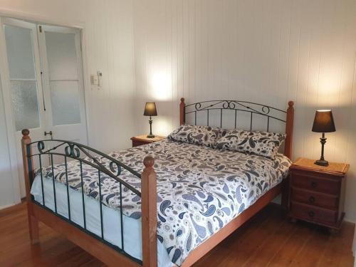 a bedroom with a bed and two lamps on tables at Turtle Cottage Magnetic Island in Picnic Bay