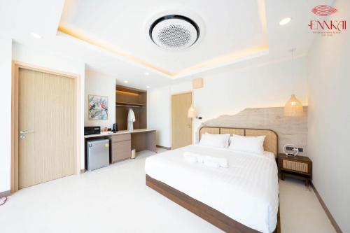 a bedroom with a white bed and a kitchen at ENNKAI Beachfront Resort Koh Larn in Pattaya Central