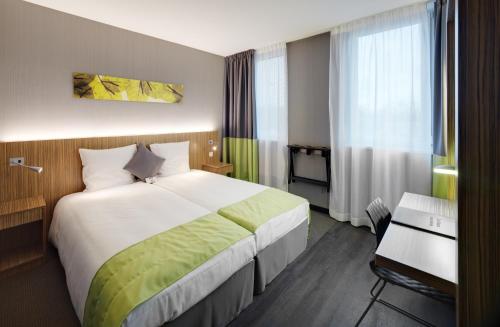 Habitación de hotel con cama grande y escritorio. en BEST WESTERN Hotel Brussels South en Ruisbroek