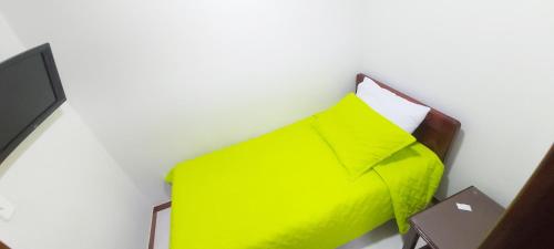 a bed with a yellow pillow and a table at Hotel Paucura in Pácora