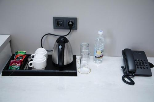a kitchen counter with a black tea kettle and a phone at Zodiac in Atyrau