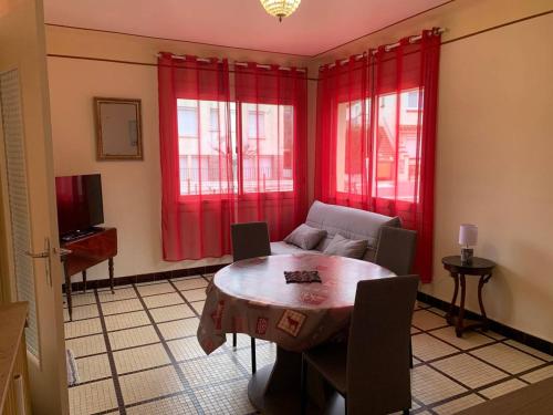 - un salon avec une table et des rideaux rouges dans l'établissement Charmant F2 avec jardin et climatisation à Amélie-les-Bains-Palalda - FR-1-703-148, à Amélie-les-Bains-Palalda