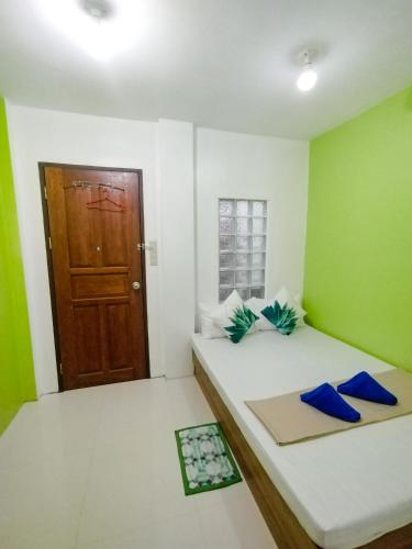two beds in a room with green walls and a door at Joyful Guest House in El Nido