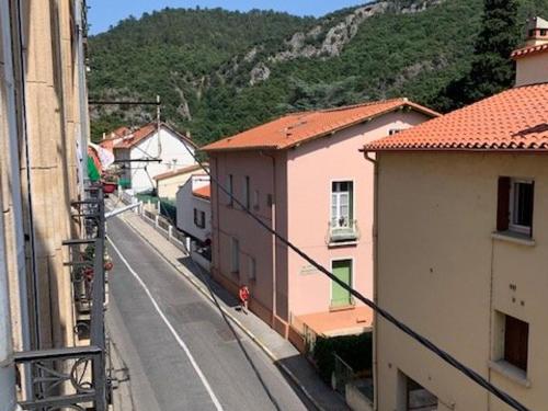 une rue urbaine avec des bâtiments et une montagne dans l'établissement Studio Mezzanine 20m², 2 pers, Parking, Ascenseur, Amélie-les-Bains - FR-1-703-150, à Amélie-les-Bains-Palalda