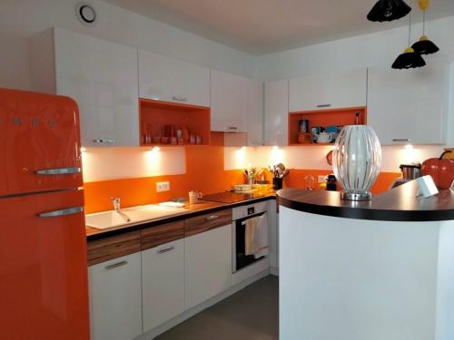 La cuisine est équipée de placards blancs et d'un réfrigérateur rouge. dans l'établissement Maison rénovée avec goût, proche plage et marché, 6 couchages, terrasse, Wi-Fi, non fumeur - FR-1-331-220, à Les Sables-dʼOlonne