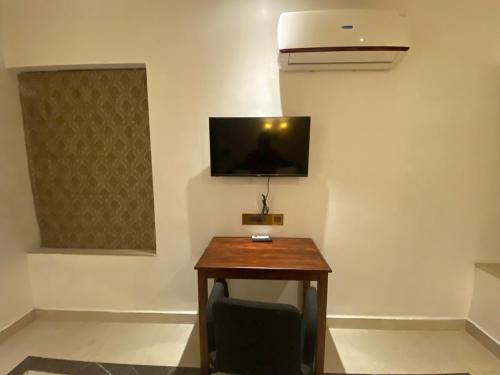 Habitación con escritorio y TV en la pared. en Queen's en Thiruvananthapuram