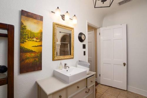 un baño con lavabo y una pintura en la pared en New! Spanish Gem-HotTub-Pool-Mins to River Walk, en San Antonio