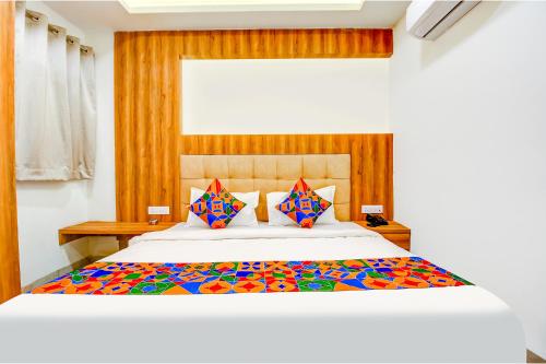 a bedroom with a large bed with colorful sheets and pillows at FabHotel Prime Purple Orchid in Bhopal