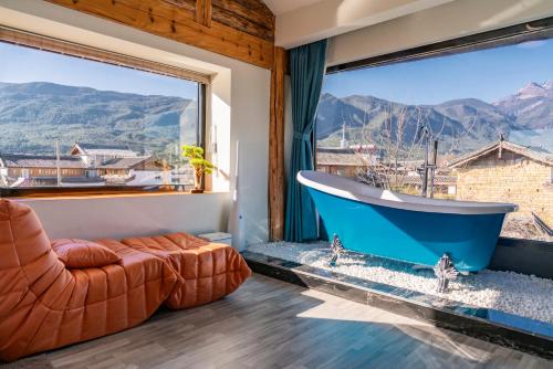 a bathroom with a tub and a couch and a large window at 玉龙白沙普宿客栈 in Lijiang