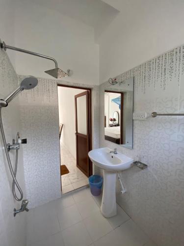 a bathroom with a sink and a shower and a mirror at senarathna guest house in Weligama