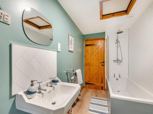 een badkamer met een wastafel, een bad en een spiegel bij Barn House in Friskney