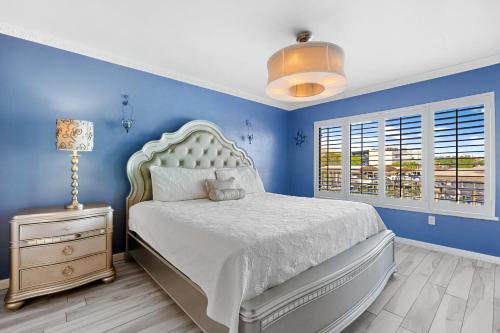 um quarto com paredes azuis e uma cama com uma colcha branca em Santa Maria 110 em Fort Myers Beach