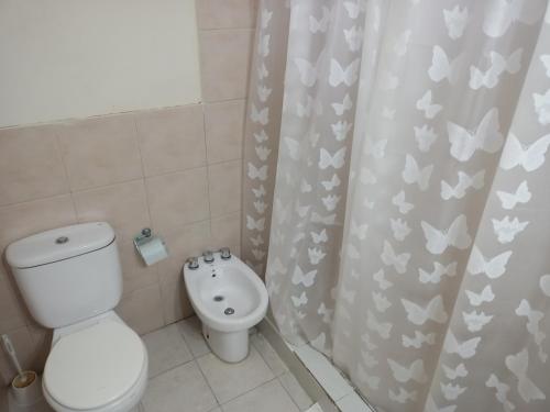 a bathroom with a toilet and a shower curtain with butterflies at ALOHA HOSTEL by BUDA BEACH in Puerto Pirámides