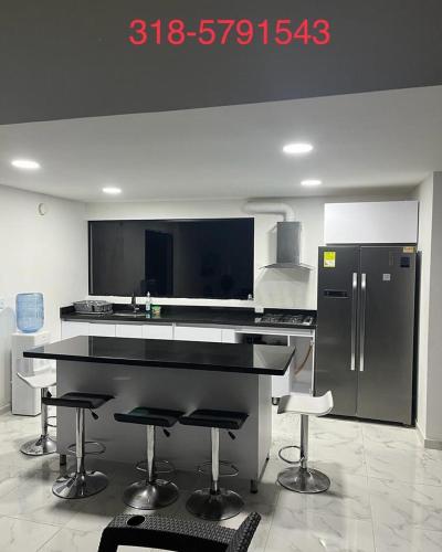 a kitchen with a black counter and a refrigerator at Villa lili, Carmen de Apicala condominio San Simon in Carmen de Apicalá