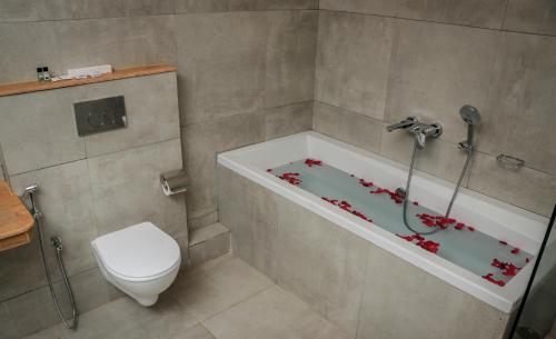 a bathroom with a toilet and a tub with red flowers on it at Sia Signature Calangute in Calangute