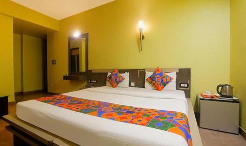 1 dormitorio con 1 cama blanca grande con sábanas coloridas en FabHotel Elements Inn, en Patna