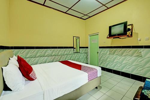 1 dormitorio con 1 cama y TV de pantalla plana en OYO 92282 Hotel Muria, en Yogyakarta
