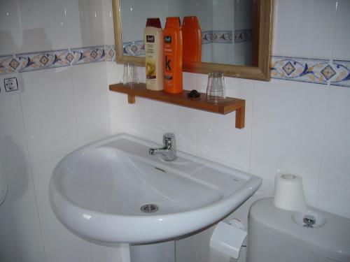 La salle de bains est pourvue d'un lavabo blanc et de toilettes. dans l'établissement Apartamentos Alamare, à Séville