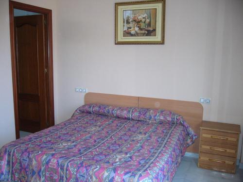 - une chambre avec un lit et une photo sur le mur dans l'établissement Apartamentos Alamare, à Séville