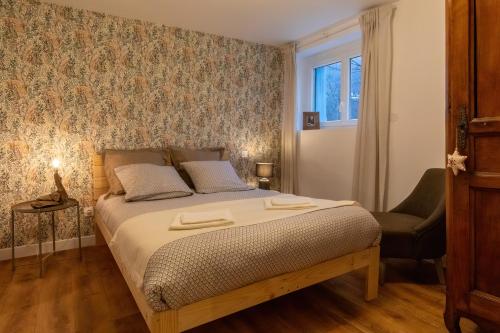 a bedroom with a bed with a chair and a window at Les appartements de Clélia in Ax-les-Thermes