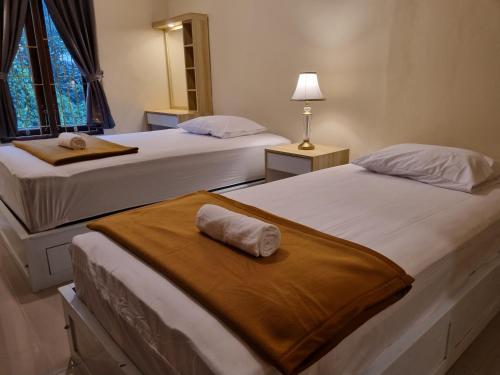 ein Schlafzimmer mit zwei Betten mit Handtüchern darauf in der Unterkunft D'Aurora Homestay in Timuran