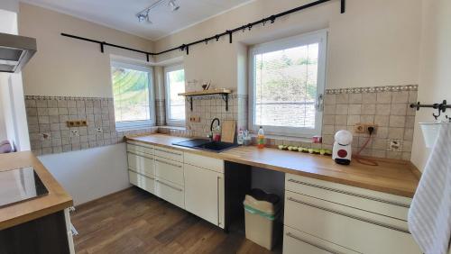 a kitchen with white cabinets and a sink and two windows at Vila nad Liptálem - Celý objekt, poblíž domu je rekreační oblast Všemina in Vsetín