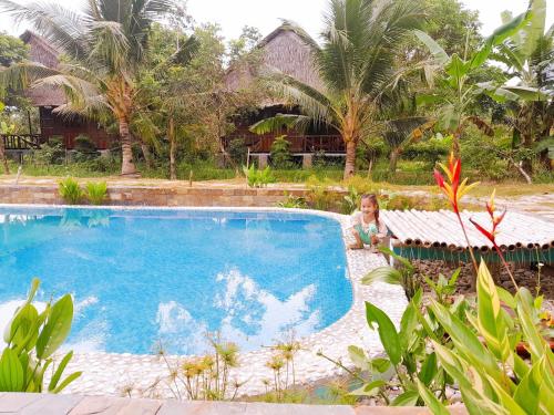 uma menina sentada ao lado de uma piscina em Green Village Mekong em Can Tho