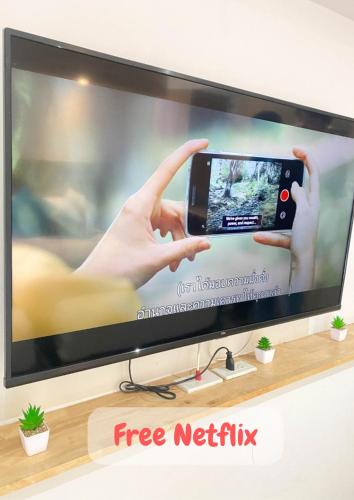a television screen with a person holding up a cell phone at 48 Ville Donmuang Airport in Bangkok