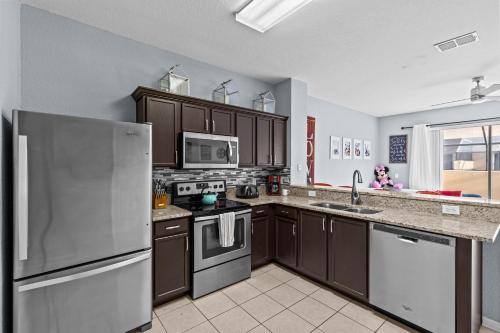 a kitchen with stainless steel appliances and brown cabinets at The Wish House, just miles from Disney World in Orlando