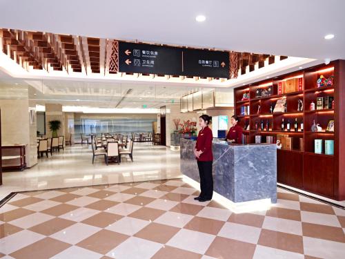 a man standing at a counter in a hotel lobby at 潍坊富华大酒店B座 The Farrington Hotel B in Weifang