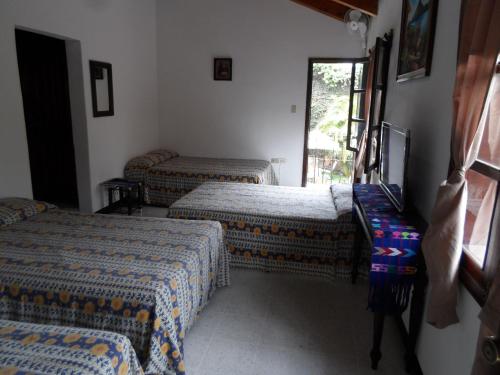 a room with three beds and a window at Casa Landivar Hotel in Antigua Guatemala