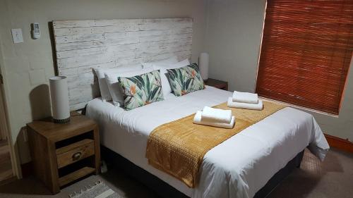 een slaapkamer met een groot bed en 2 handdoeken bij Cottage K'Gari in Franschhoek